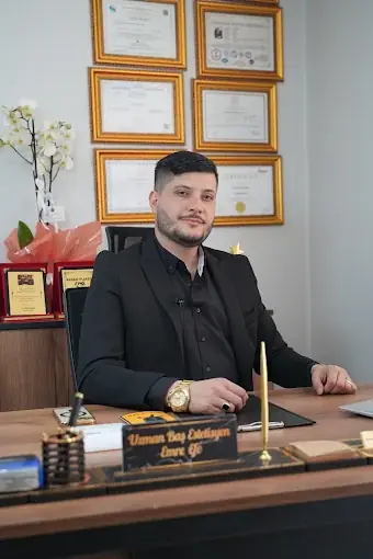 Emre Efe, DivaLüks Man'daki çalışma masasında; arkasında sertifikalar ve ödüller